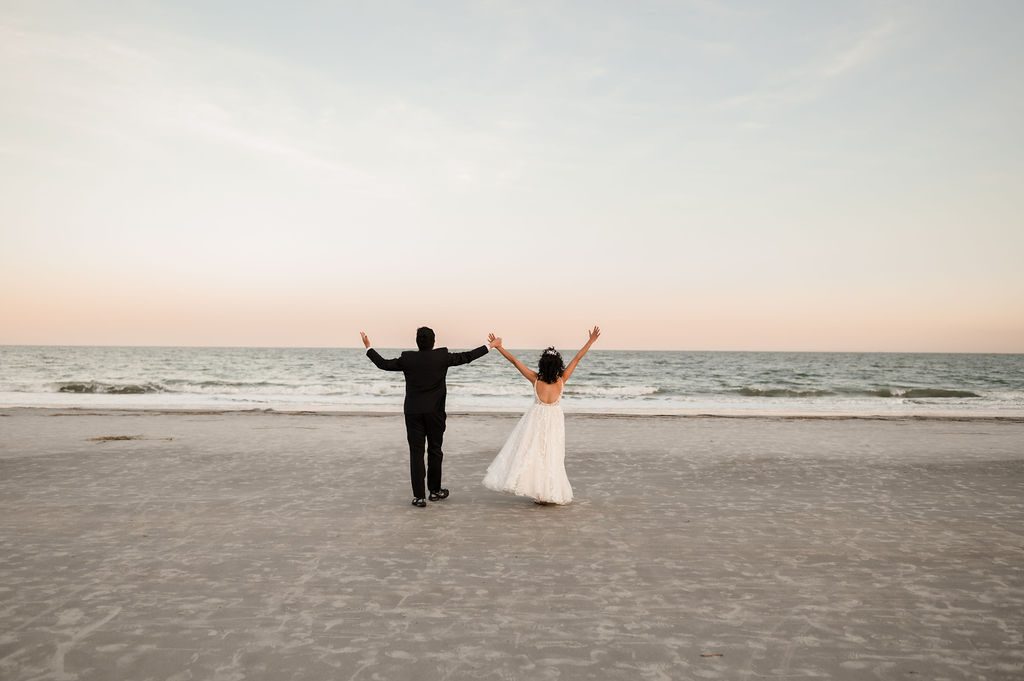 Bride and groom run towards the ocean at sunset in Hilton Head South Carolina.