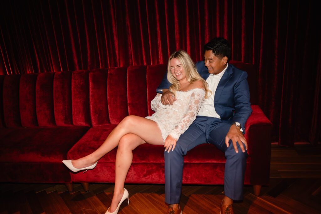 A couple cuddle on a red velvet couch at The Wellsley in Chicago, IL. 