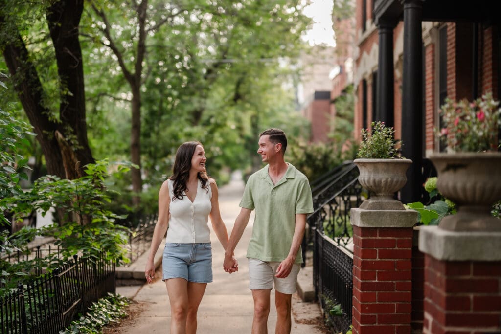 A couple holds hands walking down a tree lined street in Lincoln Park.