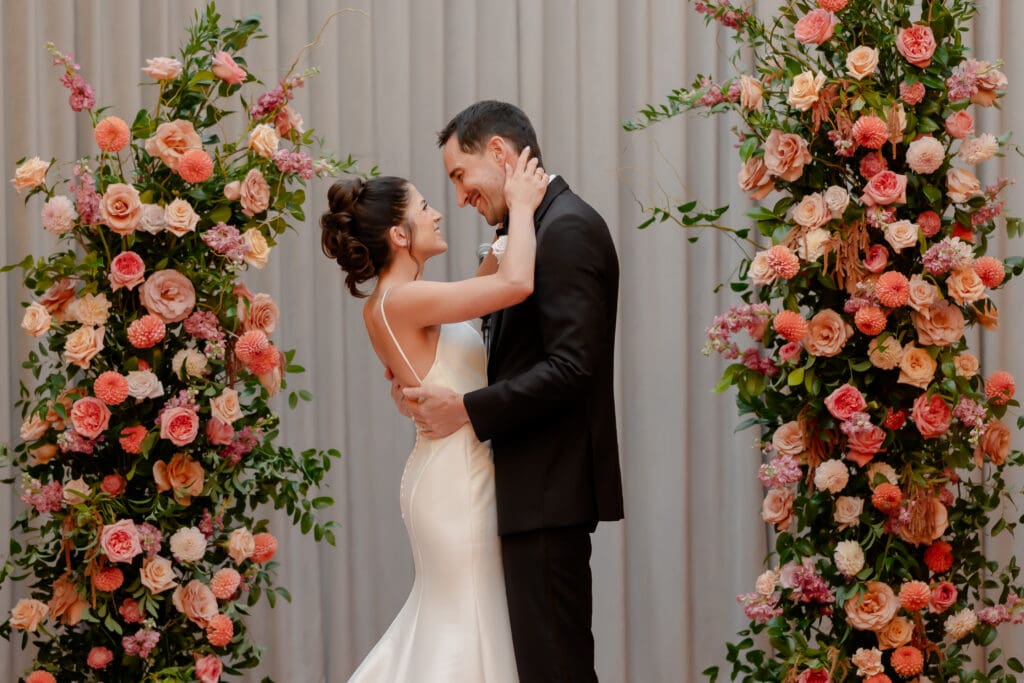 Bride and groom surrounded by pink flowers curing ceremony at Loft on Lake in Chicago.
