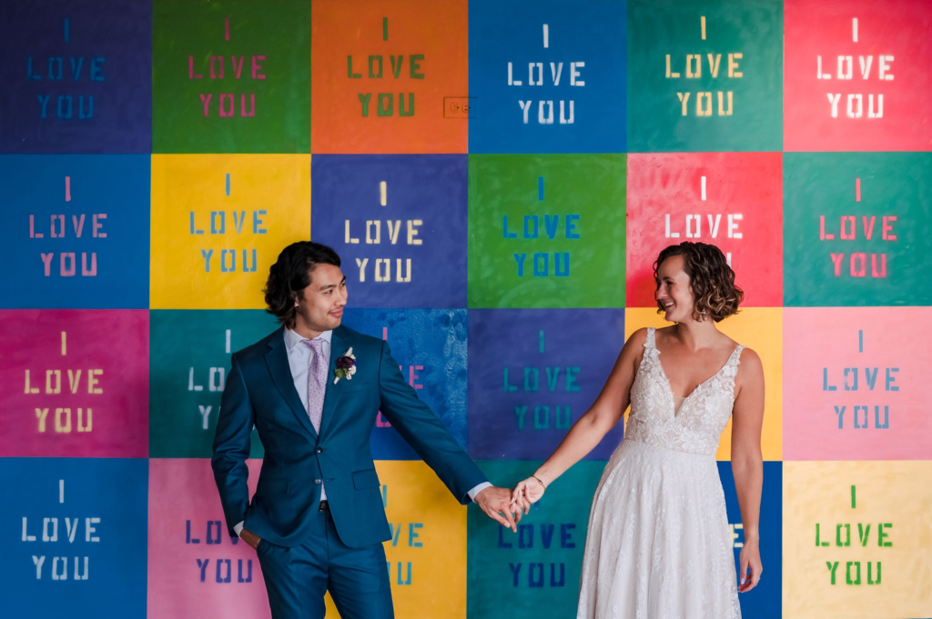 Bride and groom stand in front of I Love You mural at Lacuna Lofts 