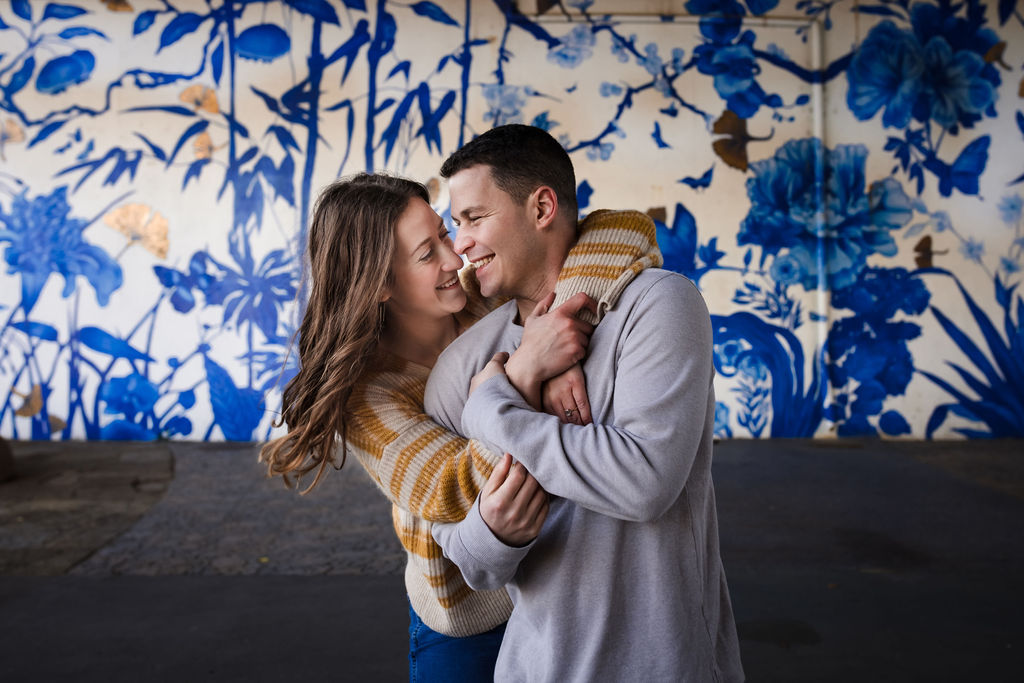 A couple hug in front of a mural at Ping Tom Memorial Park during their Chicago engagement session.