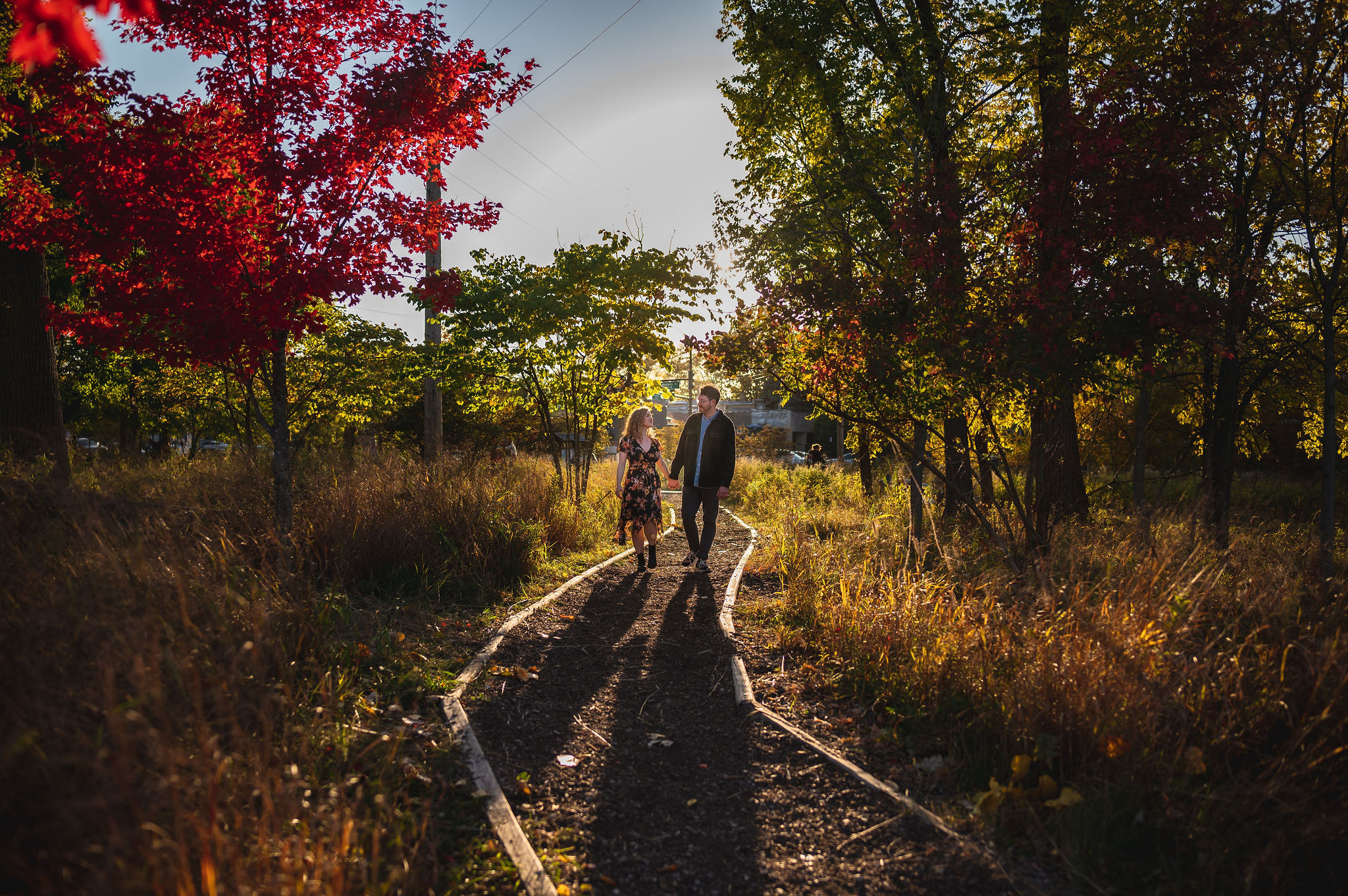 Couple. walks down path during a fall sunset at West Ridge Nature Park.