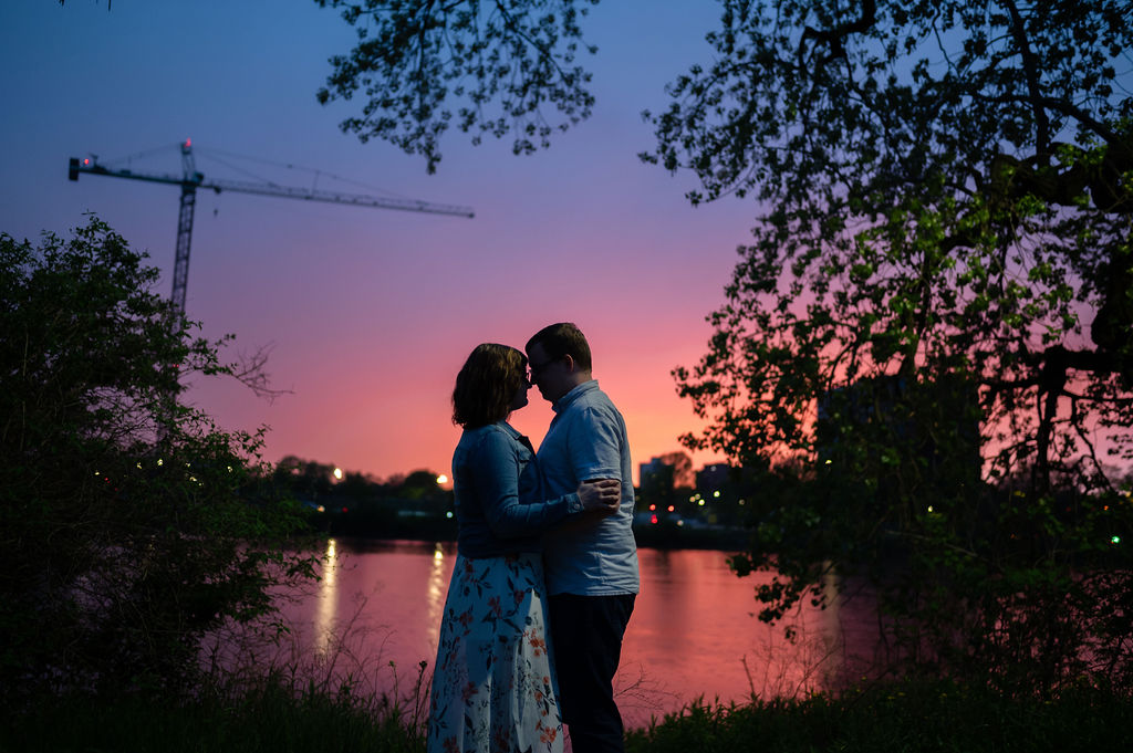 A couple embrace in front of an epic sunset at Jackson Park in Chicago