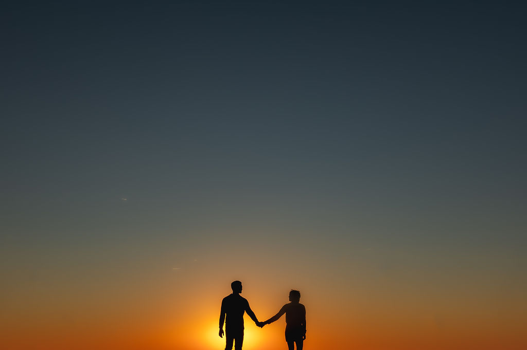 A couple hold hands at sunrise at North Avenue Beach In Chicago.