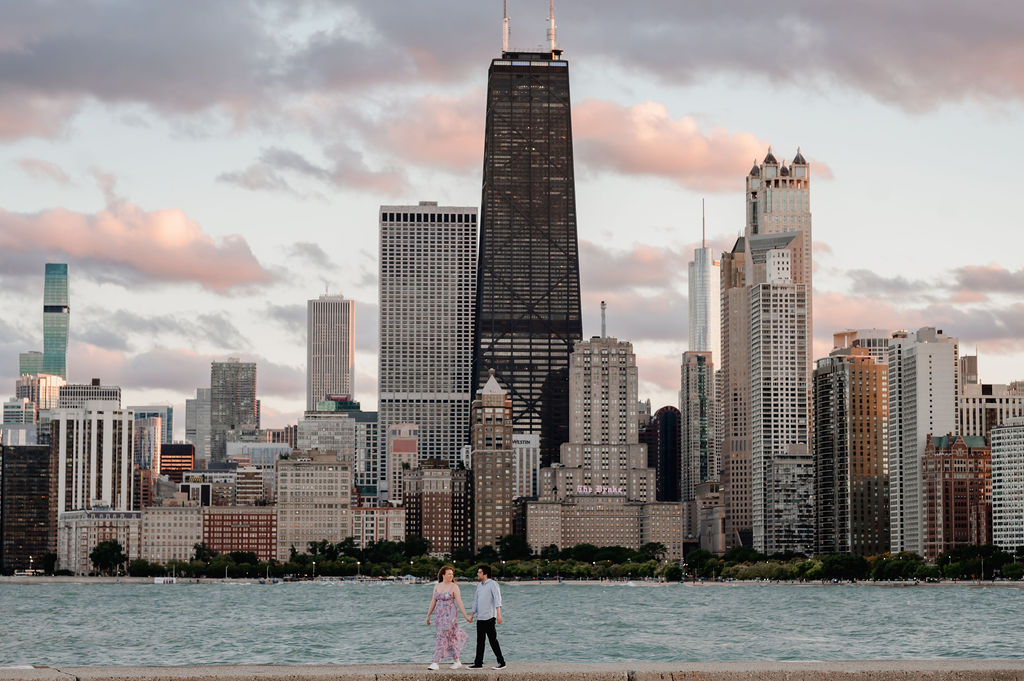 Couple hold hands in front of the Chicago Skyline at North Avenue Beach.