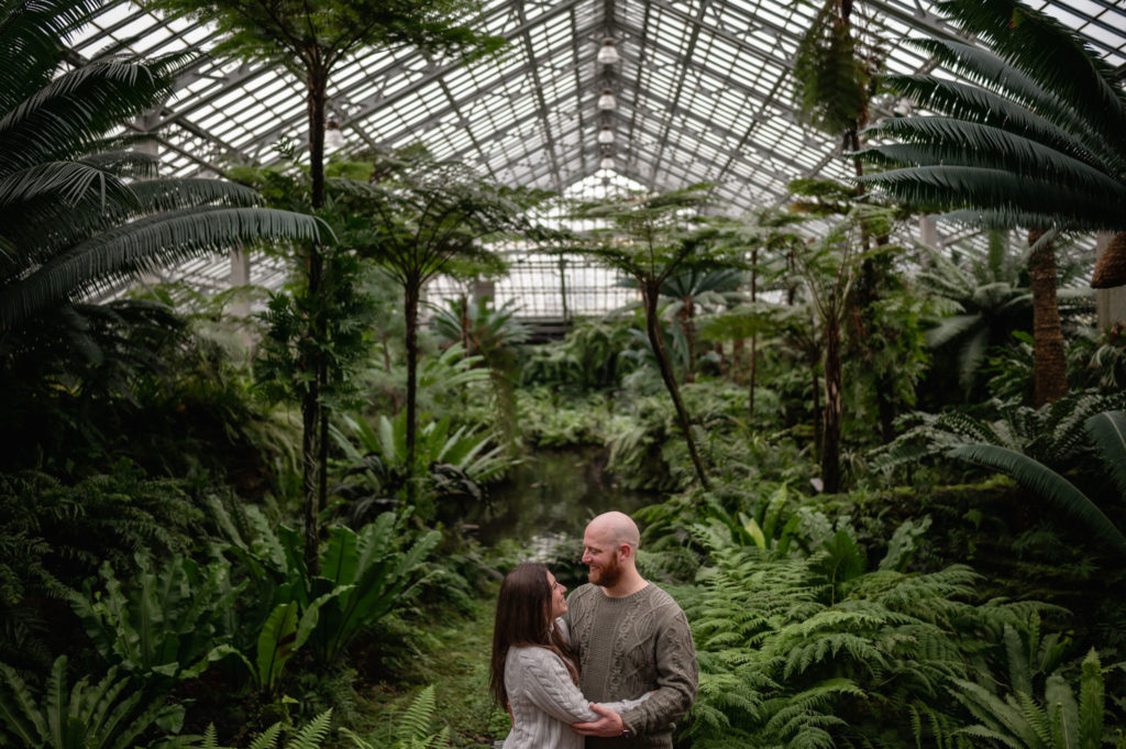 A couple embrace surrounded by greenery at the Garfield Park Conservatory.