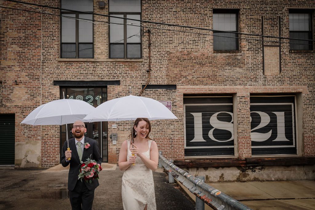 Bride and groom hold white umbrellas outside Fulton Street Collective in Chicago, IL