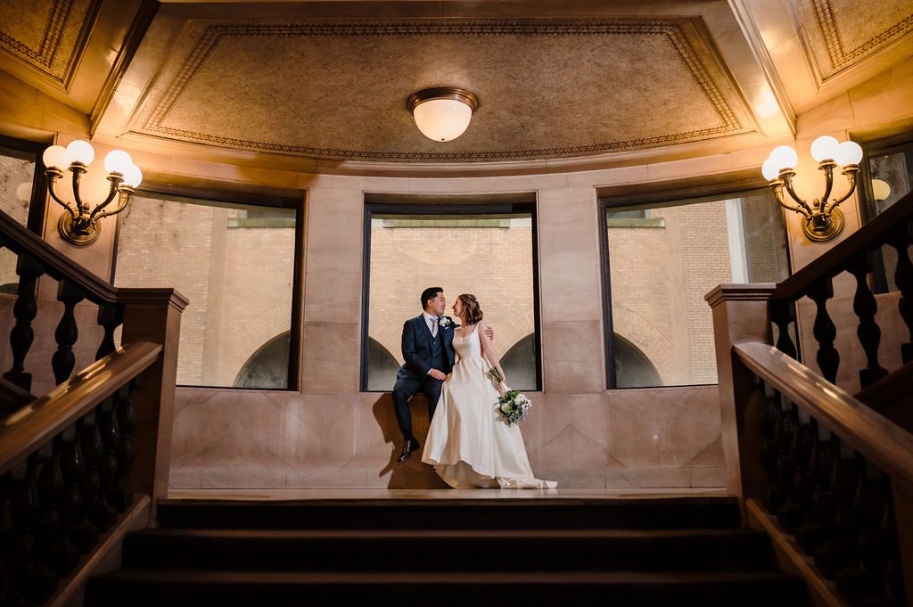 Bride and groom sit on a window at the Chicago Cultural Center.