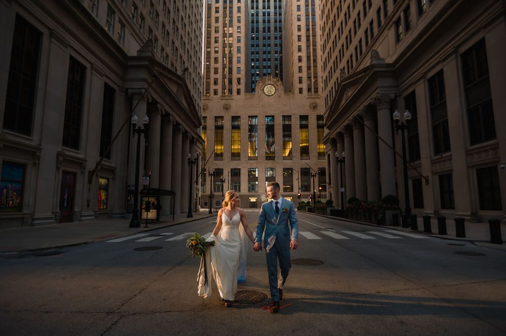 A bride and groom walk near the Chicago Board of Trade.