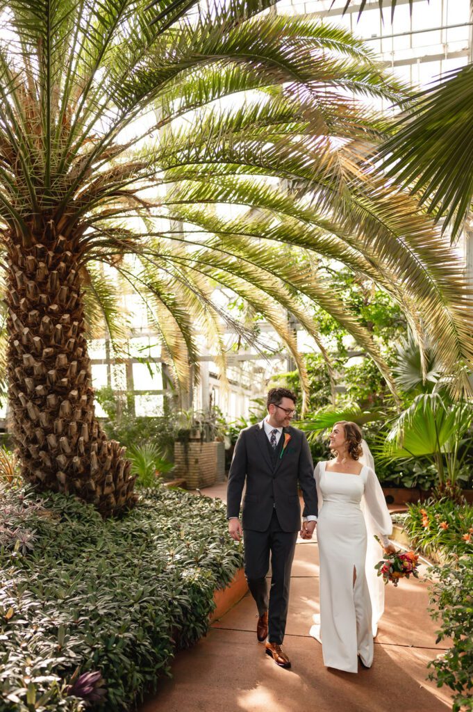Bride and groom hold hands at the Garfield Park Conservatory.