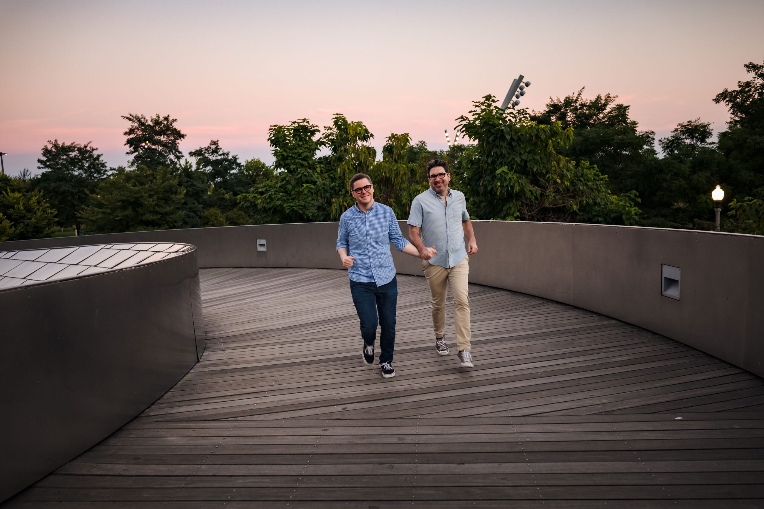 LGTBQ couple holds hands while running on a bridge in Grant Park.