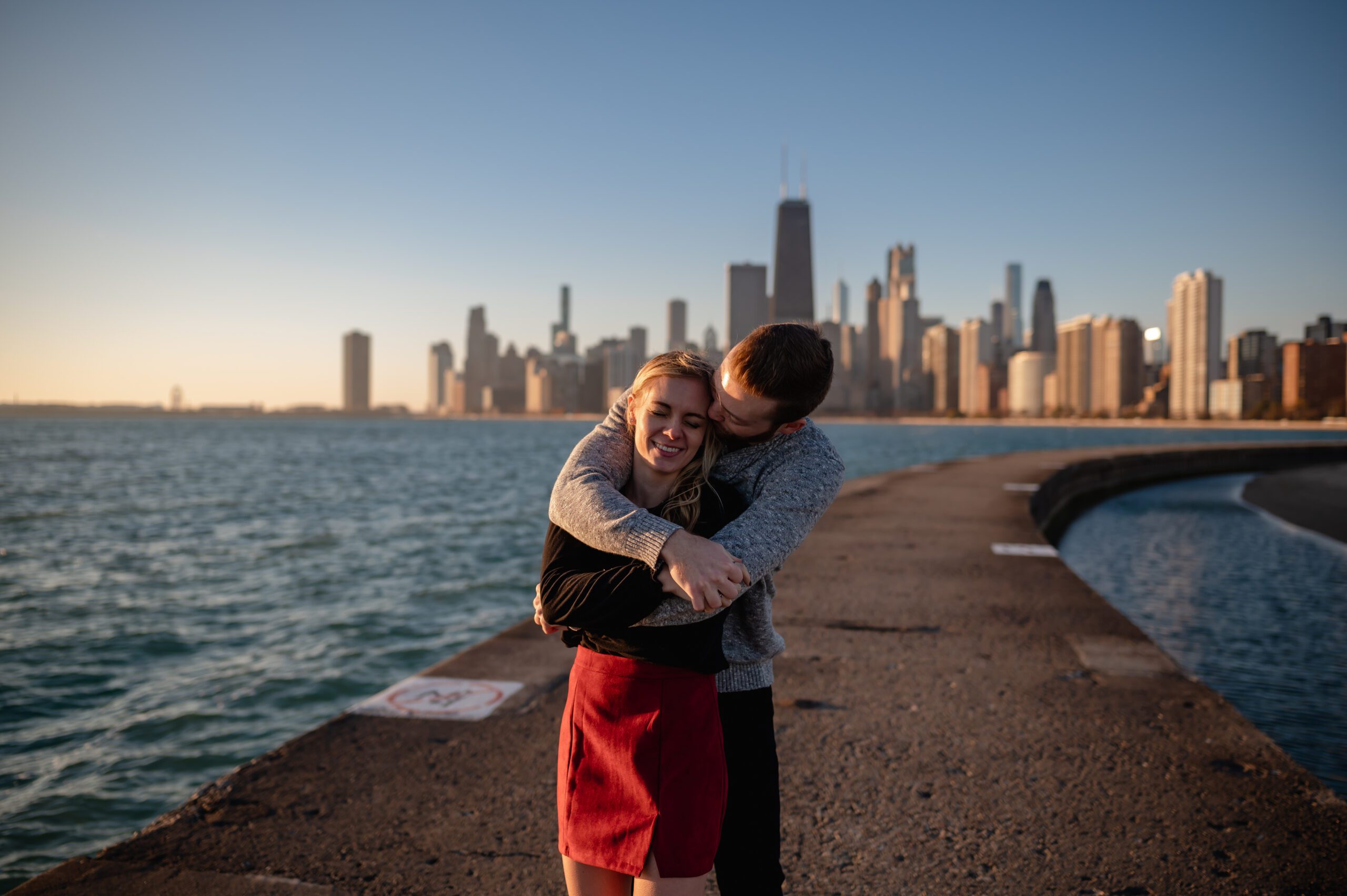 A couple embrace at sunrise at North Avenue Beach in Chicago, IL