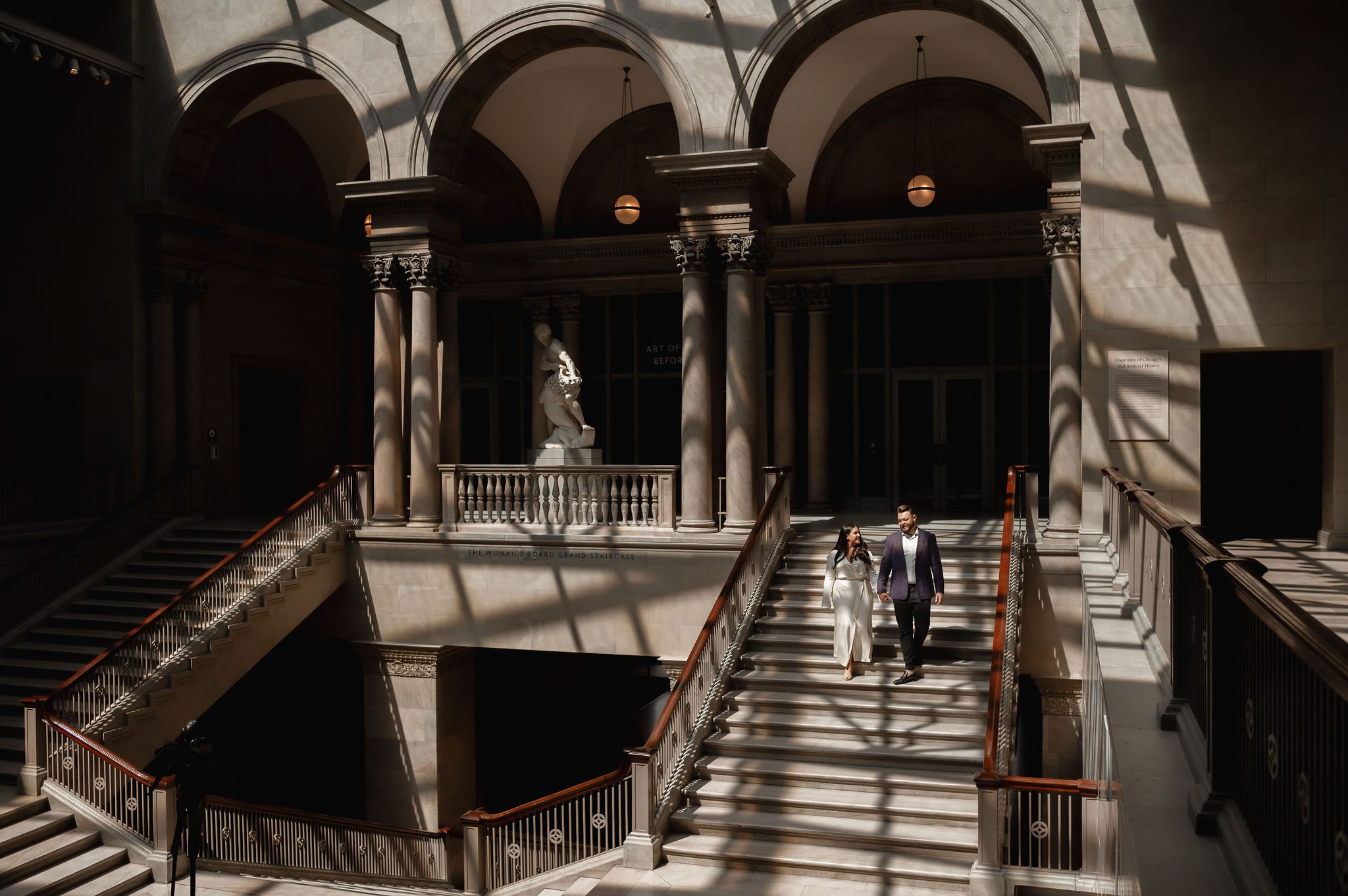 A couple walk down the grand staircase at the Chicago Art Institute