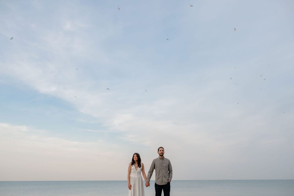 Man and women hold hands in front of Lake Michigan in Chicago at Promontory Point.