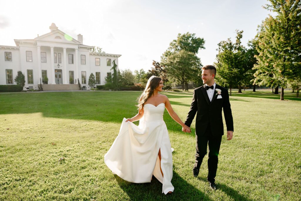 Bride and groom run on a big yard in front of Wilder Mansion 