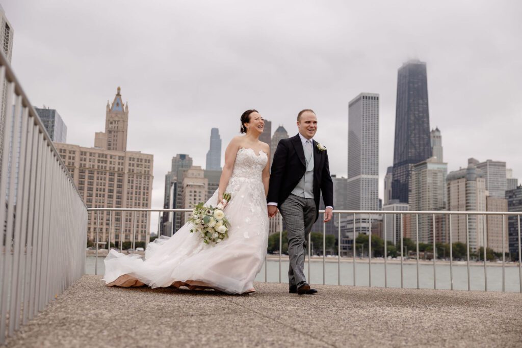 Bride and groom walk together with the Chicago skyline in the background at Milton Lee Olive Park.