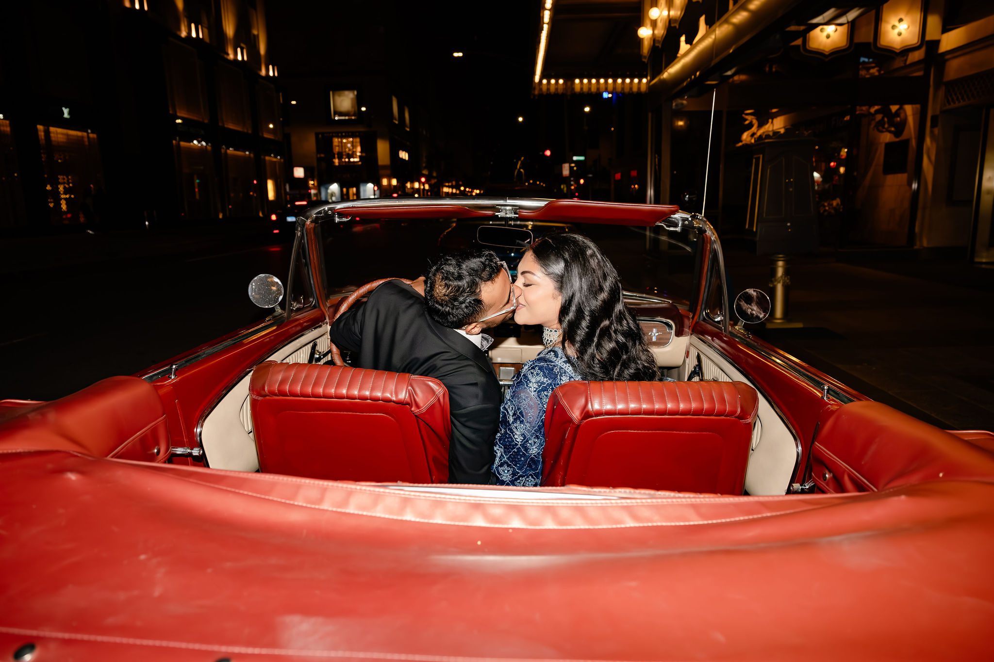 Indian couple kisses. in red Mustang after getting married at the Drake Hotel in Chicago, IL.