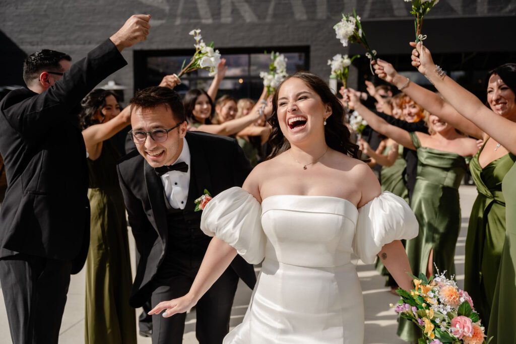 Bride and groom run under a wedding party tunnel. 