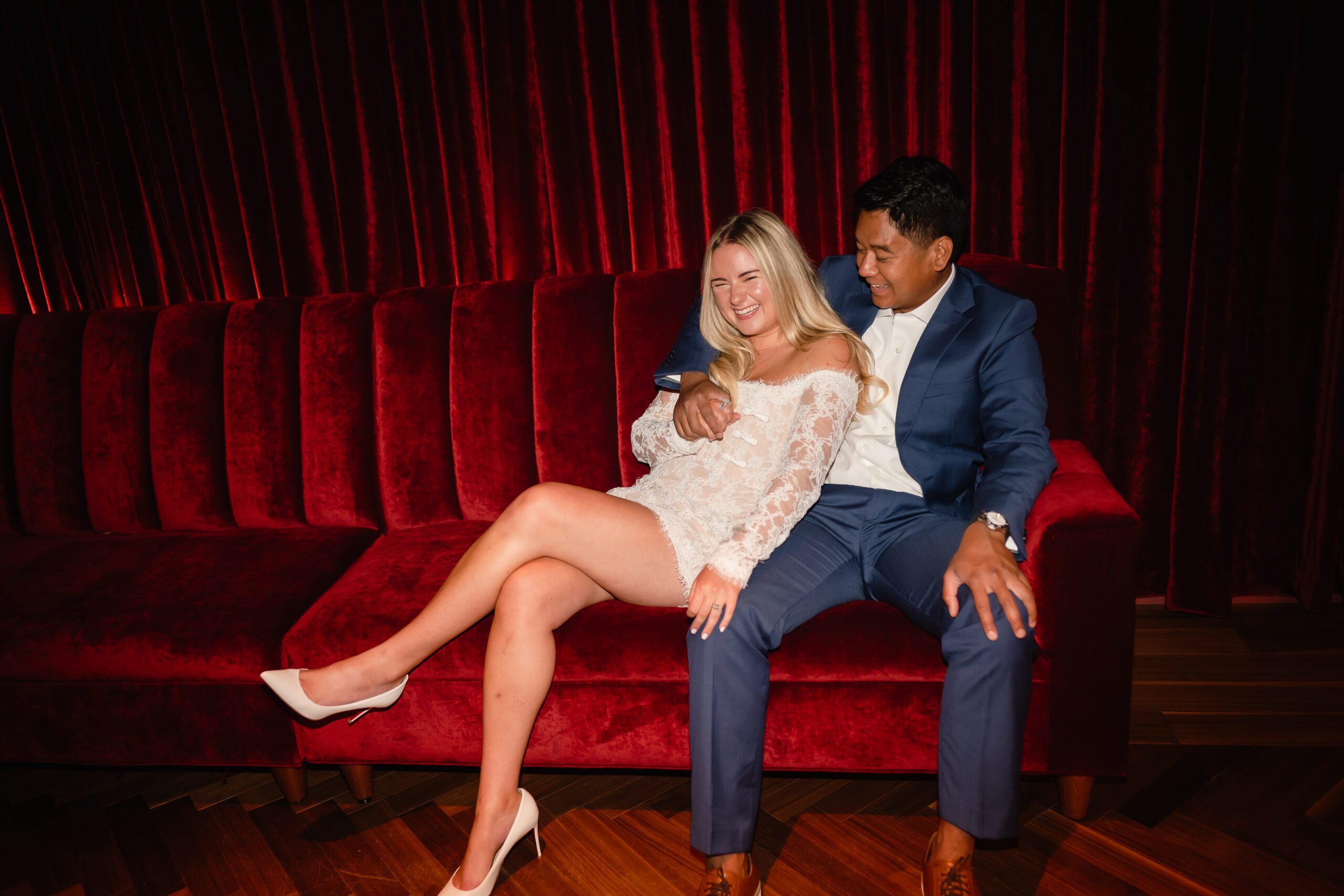 A couple cuddle on a red velvet couch at The Wellsley in Chicago, IL.