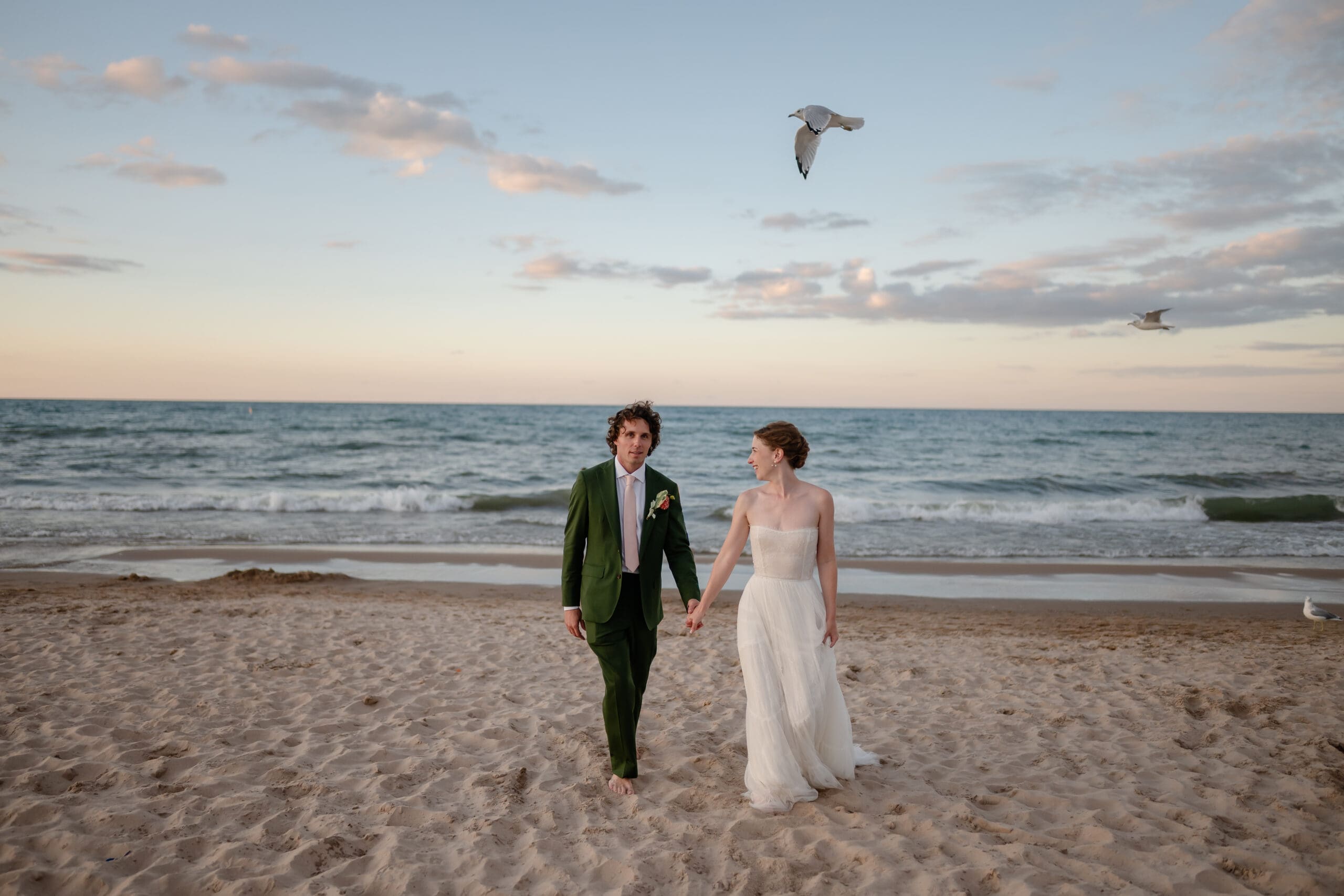 A couple walks on the beach during sunset at Gillson Park during their wedding.