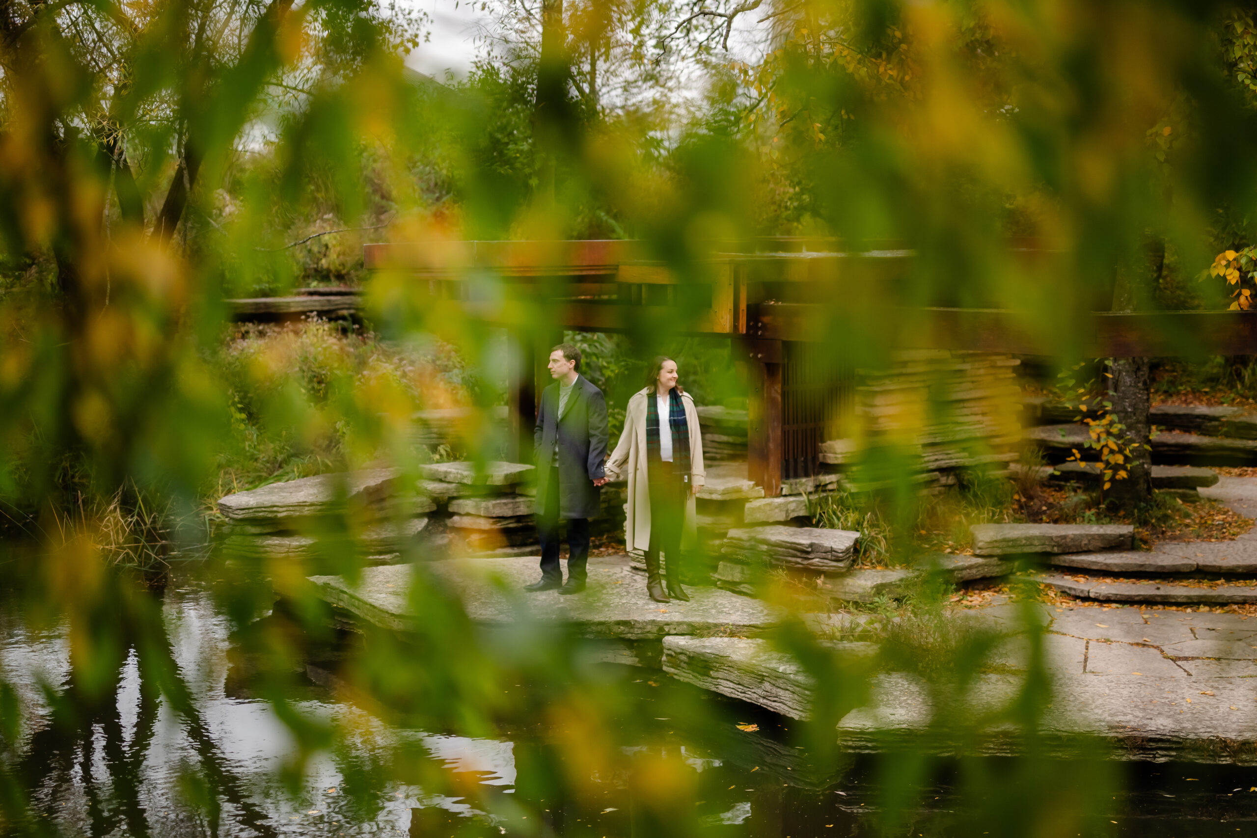A couple holds hands behind a tree in Chicago.