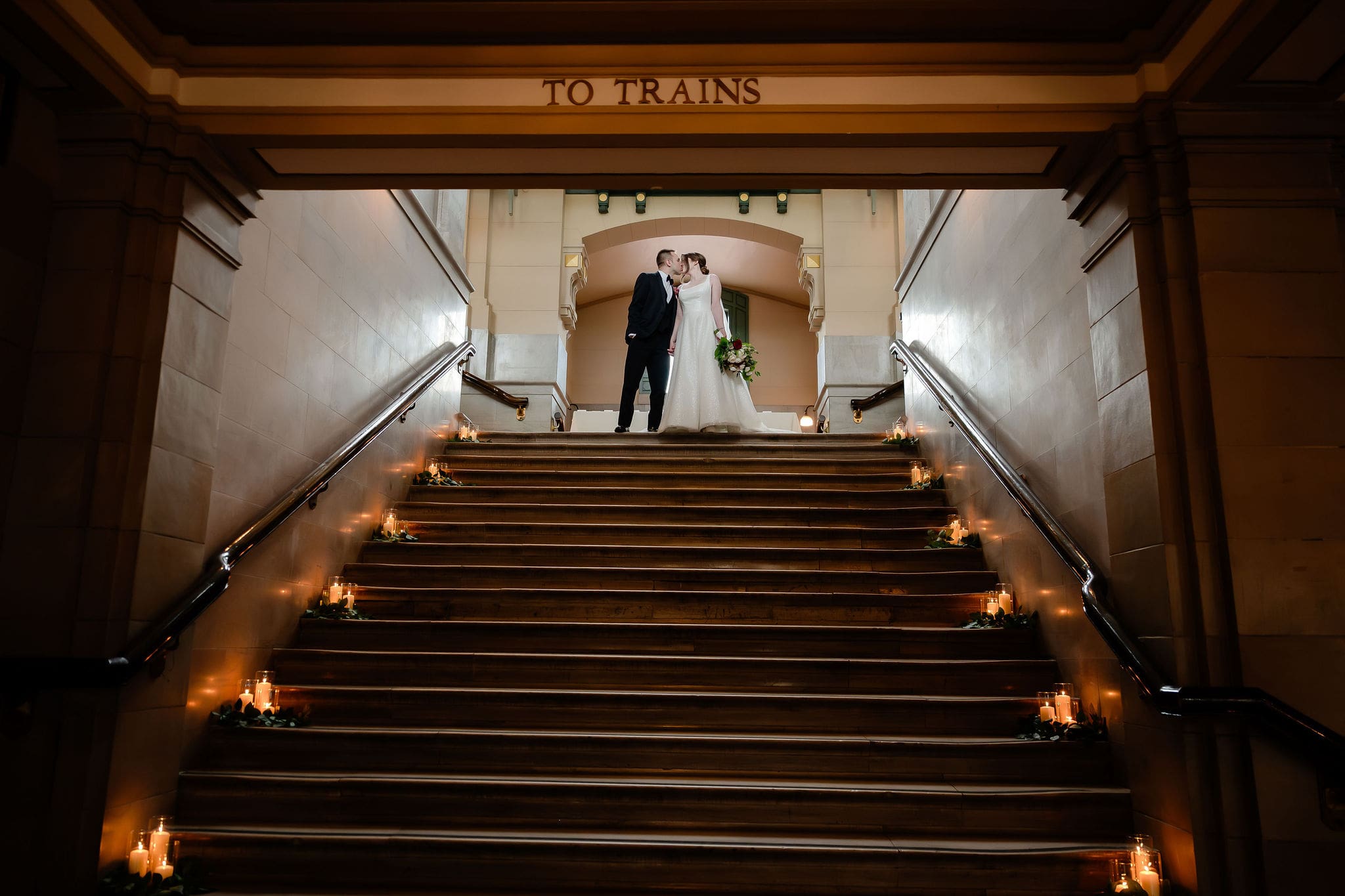 Bride and groom kiss on top of the staircase at Joliet Union Station.