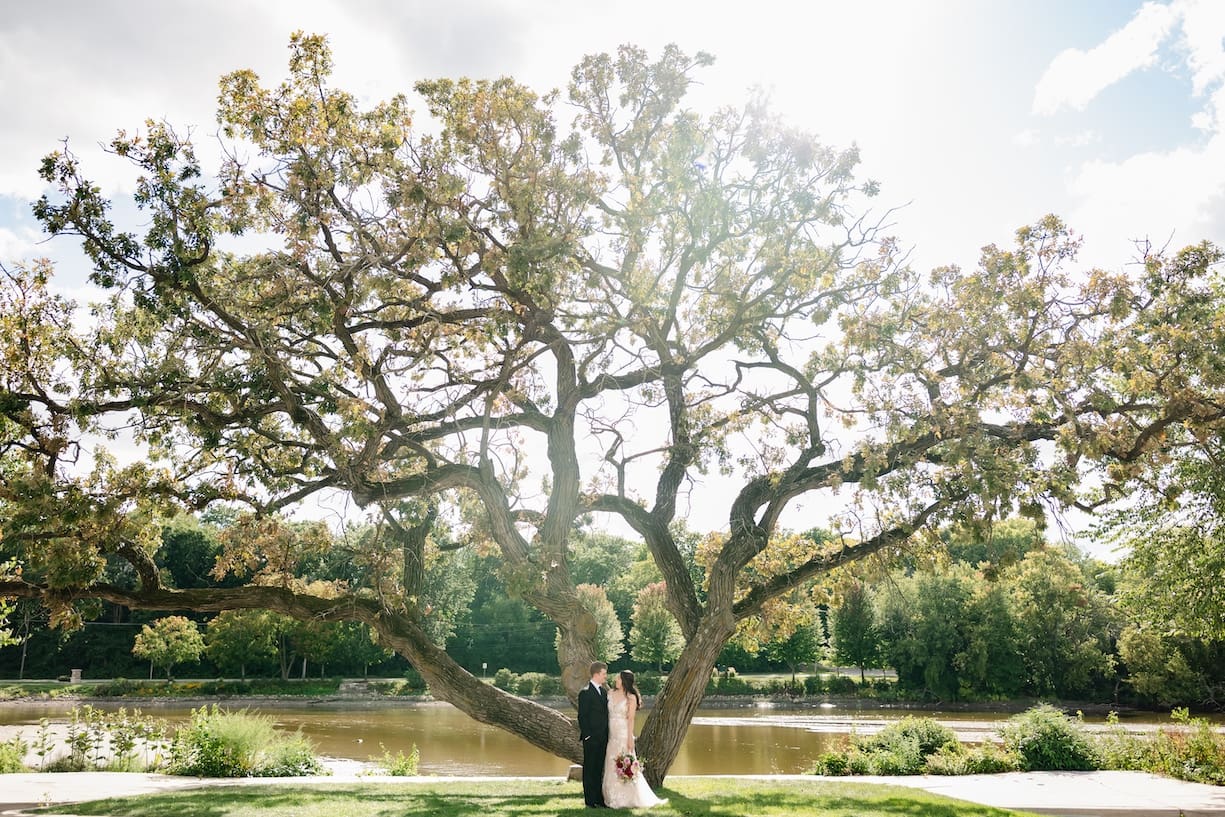 Bride and groom stand in front a big oat tree at The Brix on the Fox.