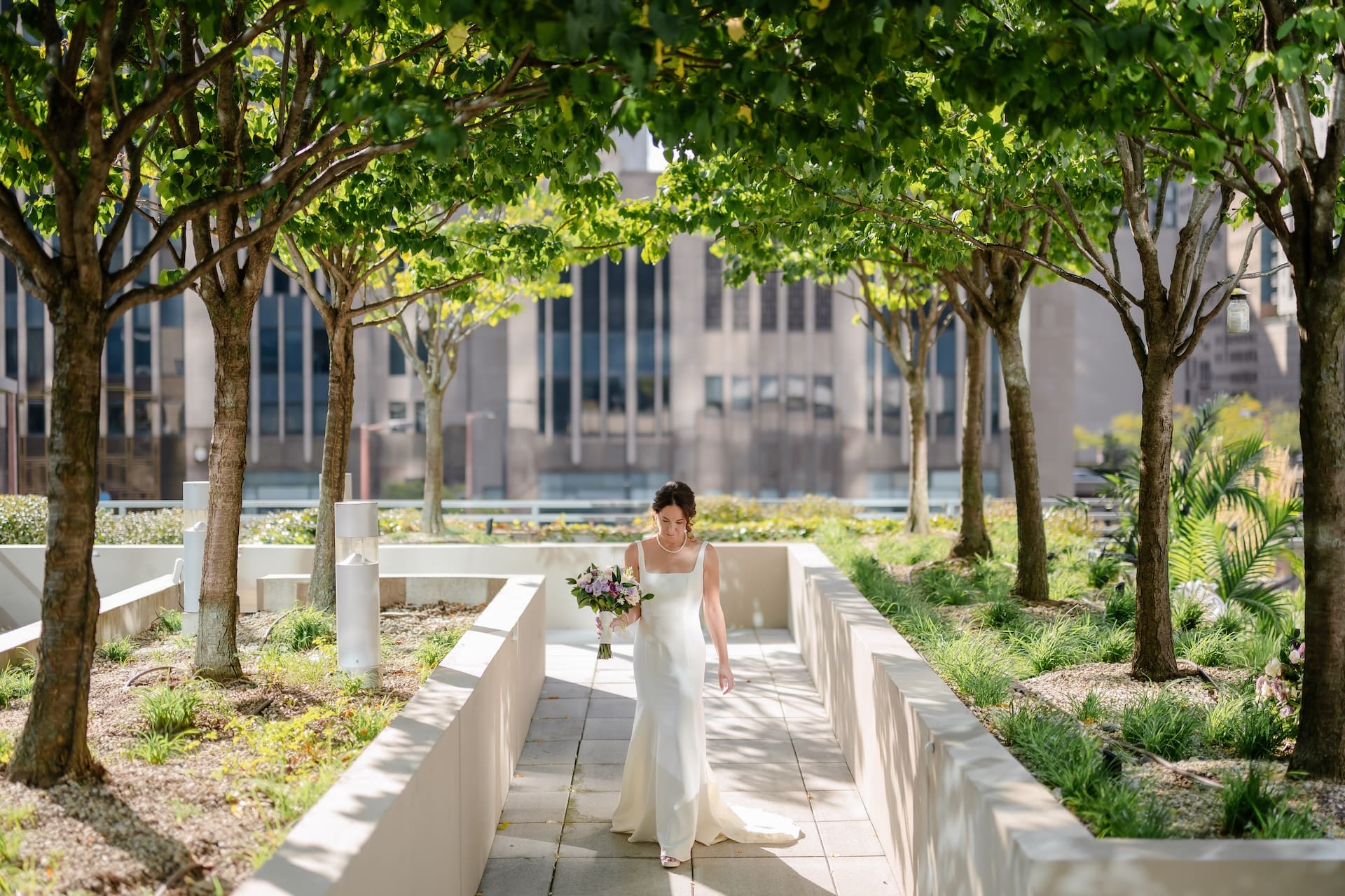 Bride walks down a rooftop path surrounded by trees at Lowes Hotel Chicago.